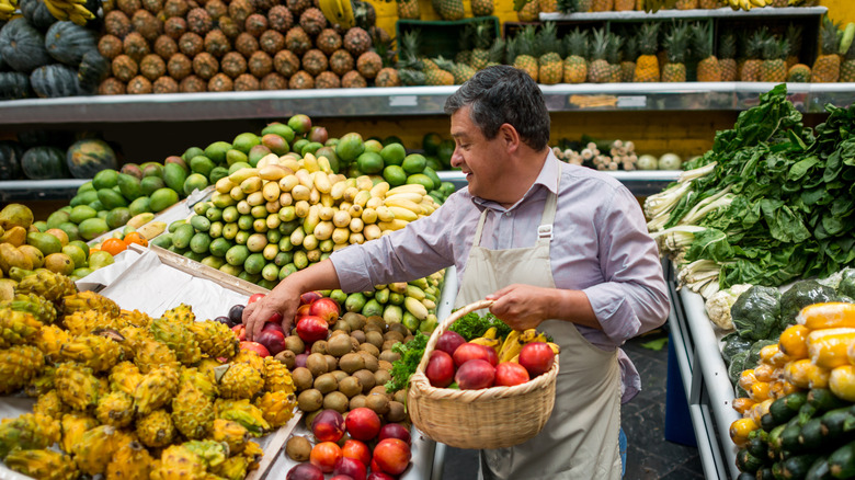 man picks up produce from grocery display.