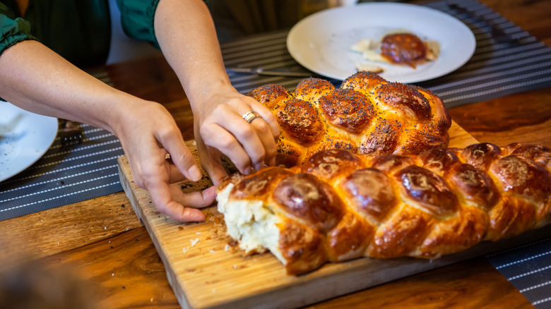 Person pulling apart challah loaves