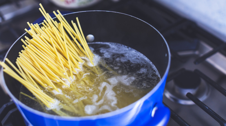 Pasta dropping into water in a blue pot