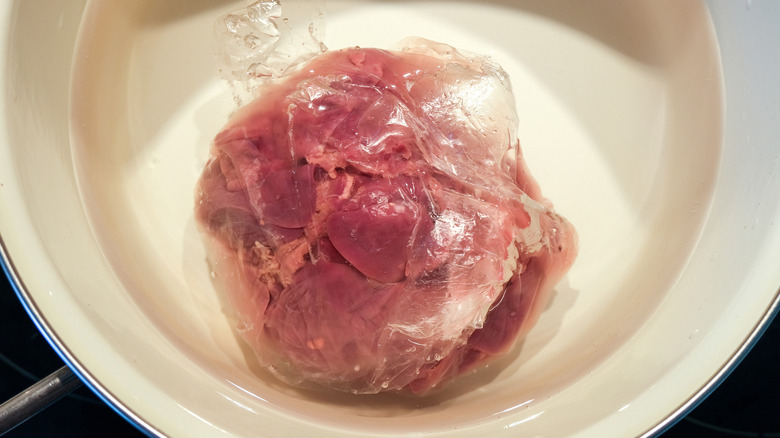 Defrosting frozen liver in a bowl.
