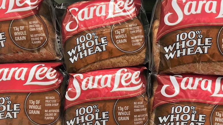 Stacks of Sara Lee Whole Wheat loaves of bread on a shelf in a store.
