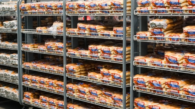 Rows of Sara Lee brand bread and buns on racks inside a bulk goods store.