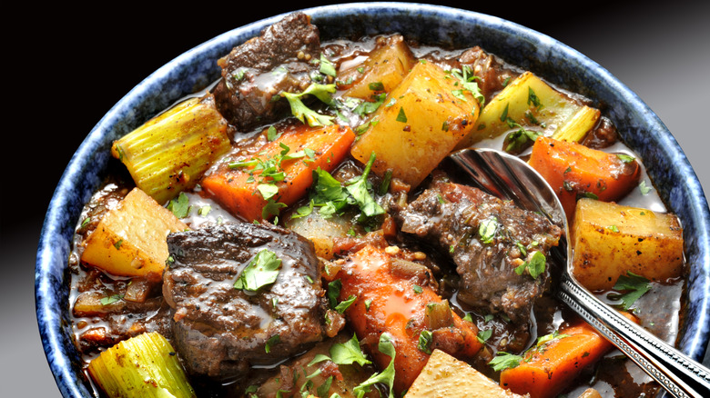 beef stew in a blue bowl with a silver spoon