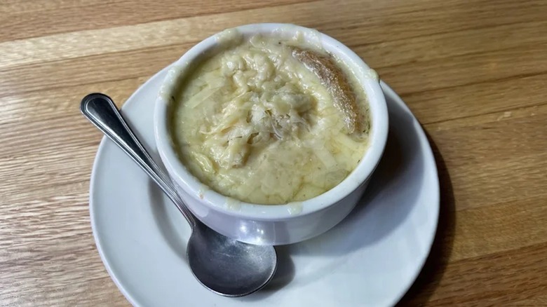The French onion soup from Applebee's served in a white bowl on top of a wooden table