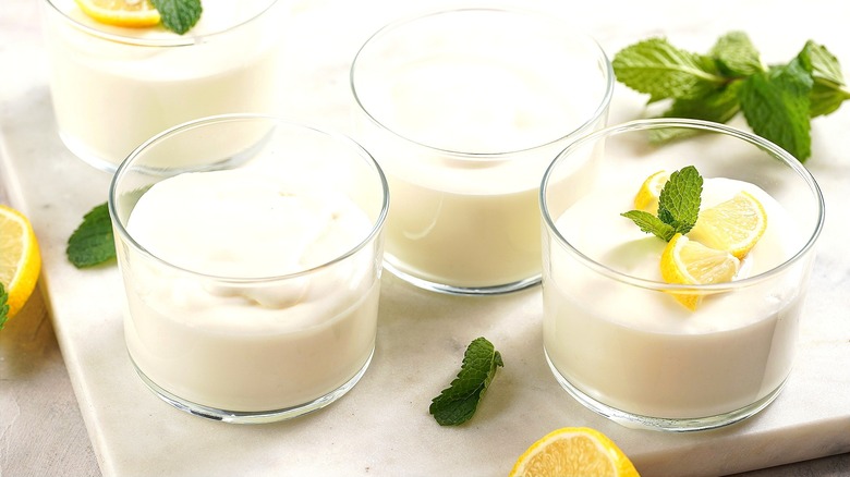 Clear short glasses filled with yogurt, lemon wedges, and mint leaves
