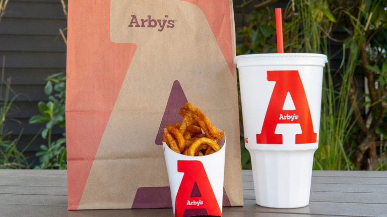 Arby's to-go bag, drink, and fries on outdoor table
