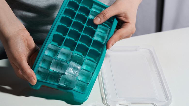 Hands removing ice cubes from silicone ice cube mold