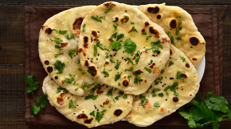 naan piled on top of a rectangular wooden serving tray