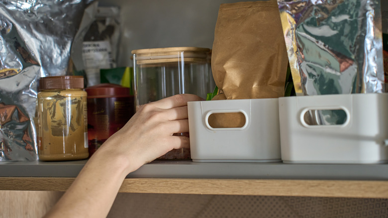 hand taking item from solid pantry shelving