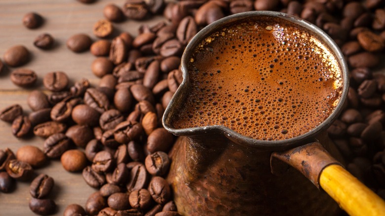 pot of Turkish coffee surrounded by coffee beans