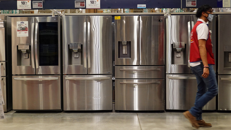 an employee walks by fridges at Lowe's