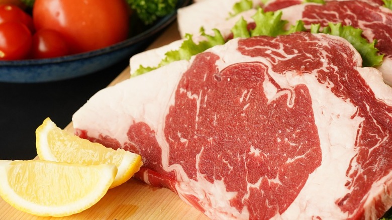 Marbled steaks arranged in a domino layer on a cutting board.