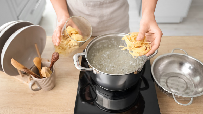 person putting pasta in water