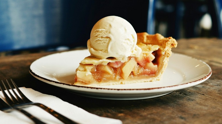 A slice of apple pie with ice cream is plated at a restaurant.