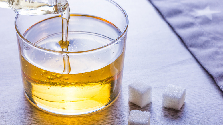 Invert sugar being poured into a clear glass next to sugar cubes