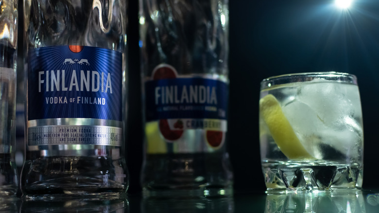 Bottles of opened vodka next to a rocks glass