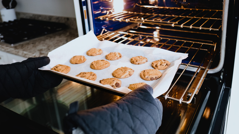 A baker taking a tray of cookies out of the oven