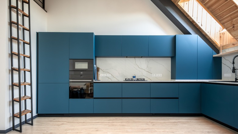 Modern kitchen with matte blue cabinets, glossy surfaces, natural colors and textures, and ample sunlight