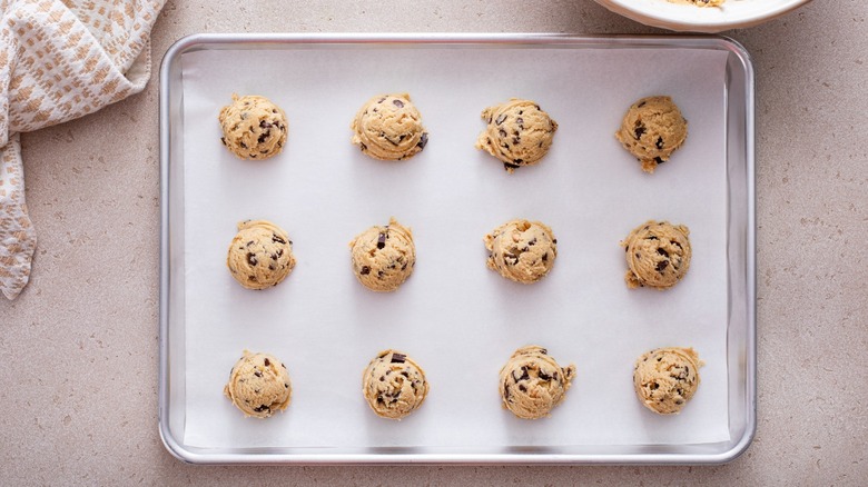 Cookie dough scooped onto parchment paper on a tray