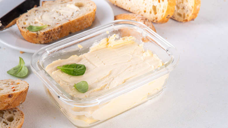 vegan butter in glass dish with sliced bread in background