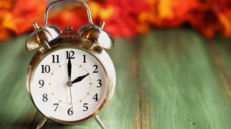 An old-fashioned alarm clock sitting on a wooden table top