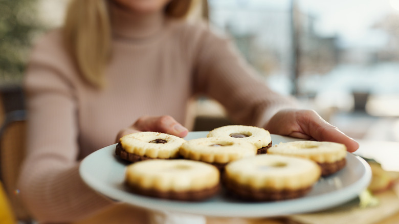 Person handing over a plate of cookies