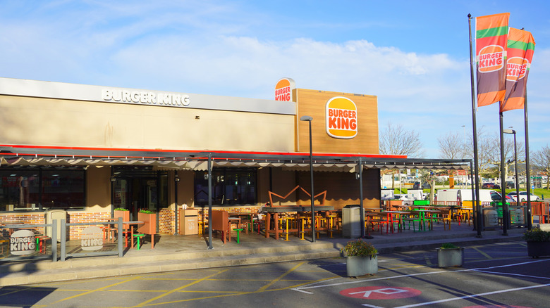 The exterior of a Burger King with flags and outdoor seating