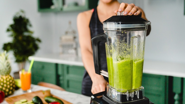 Woman blending greens in blender