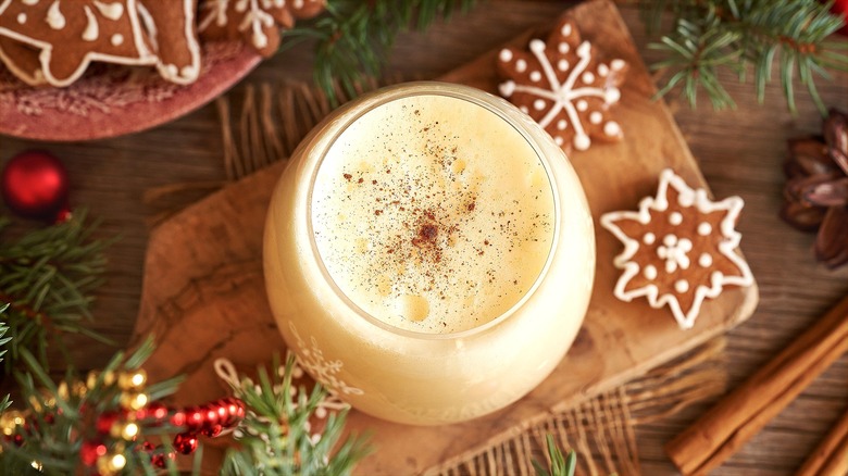 Top-down view of a clear glass filled with eggnog and topped with nutmeg