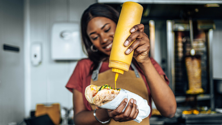 Person squeezing a mustard bottle