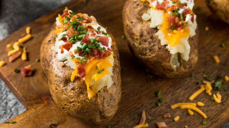 Loaded baked potatoes on a wooden board