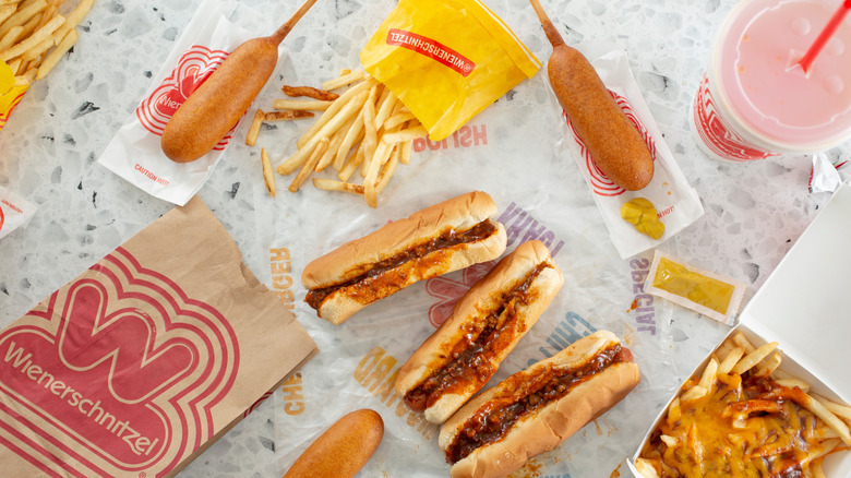 Top-view of Wienerschnitzel chili dogs, fries, corndogs, and drink