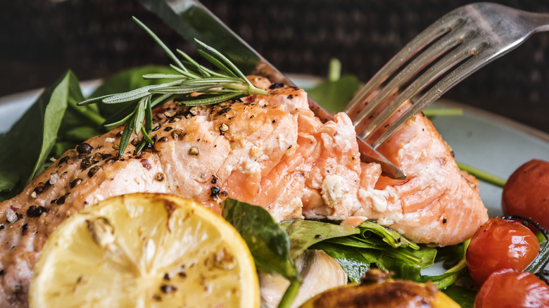A diner cutting into a cooked piece of salmon