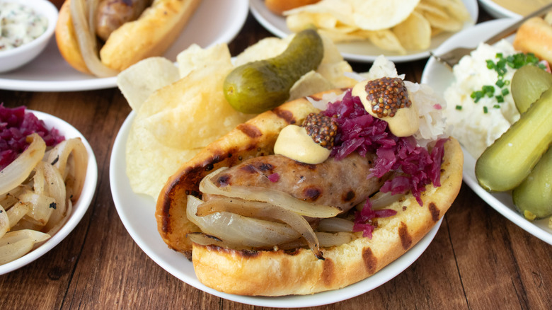 Side shot of dressed beer brats and plain beer brats on wood