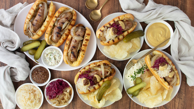Overhead shot of dressed beer brats and plain beer brats on wood