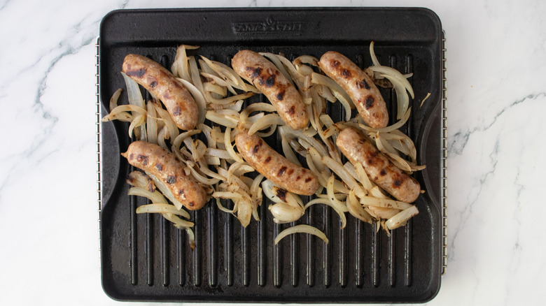 Grilled brats and onions on a large grill pan