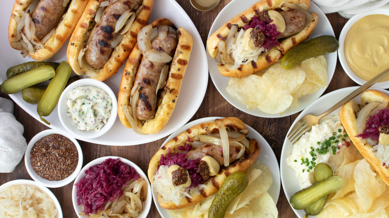 Overhead shot of dressed beer brats and plain beer brats on wood