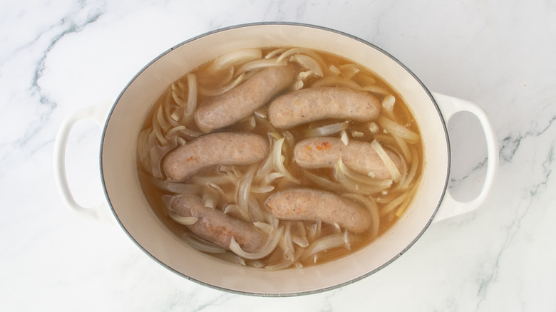 Cooked brats and onions in beer in a large Dutch oven
