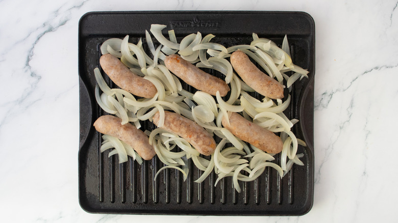 Simmered brats and onion in beer on a large grill pan