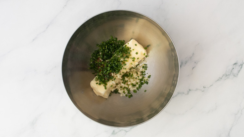Butter, herbs, and grainy mustard in a medium metal bowl