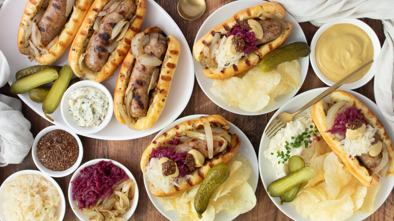 Overhead shot of dressed beer brats and plain beer brats on wood