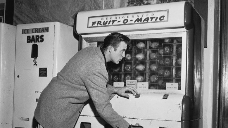 Person reaching for fruit from a Refrigerated Fruit-O-Matic machine