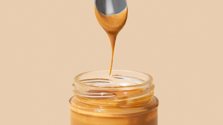 spoon being dipped into a peanut butter jar