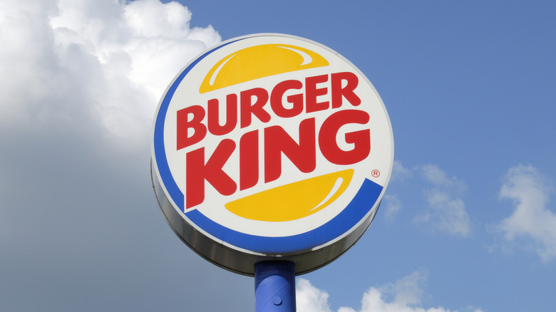 Burger King sign sits against a blue sky with clouds