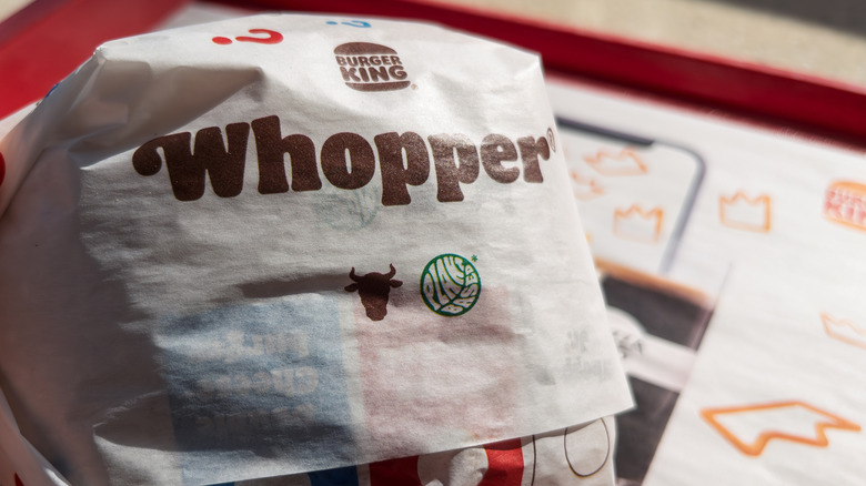 Wrapped Burger King Whopper sits on a fast food tray