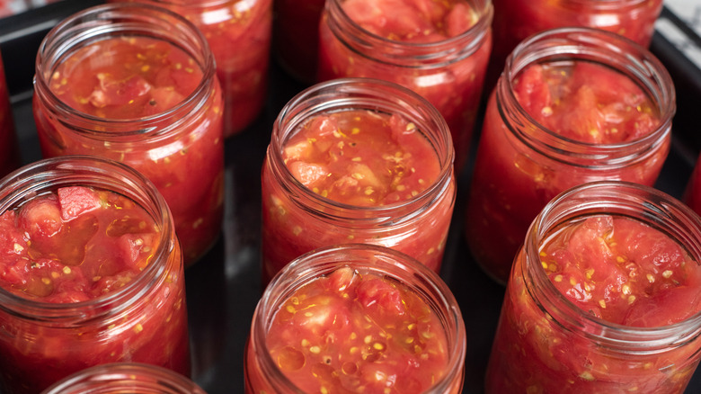 A collection of unlabeled jars of salsa with their lids taken off.