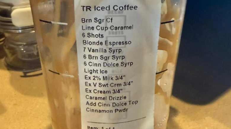 The side of a large iced coffee drink entirely covered with a list of modifications