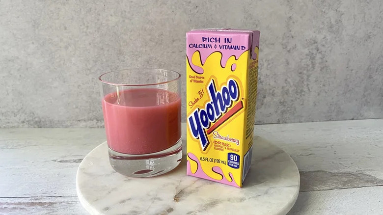 A container of Yoo-Hoo's strawberry drink sits next to a glass filled with the Yoo-Hoo drink