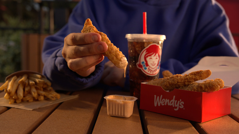 Person dipping Wendy's Tendy into Wendy's Signature Sauce