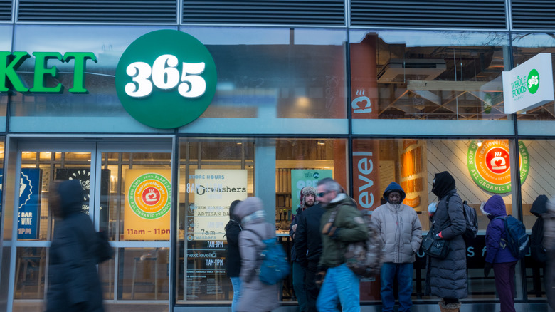 People in coats walking in front of a Whole Foods 365 Market